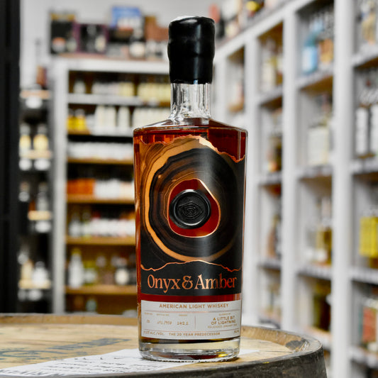 Bottle of Onyx & Amber American Light Whiskey on a barrel with shelves in the background